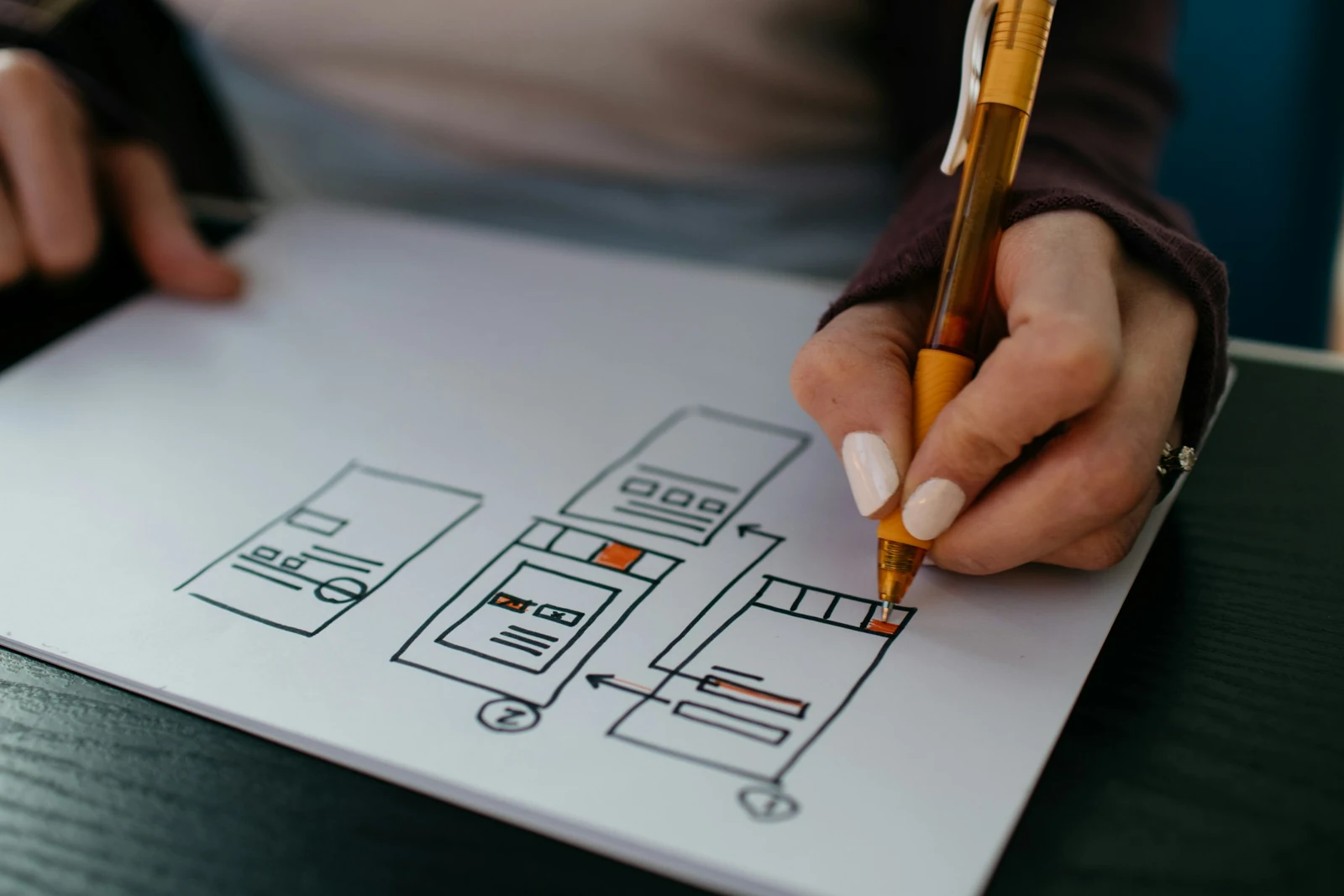 Hands sketching a website wireframe on paper